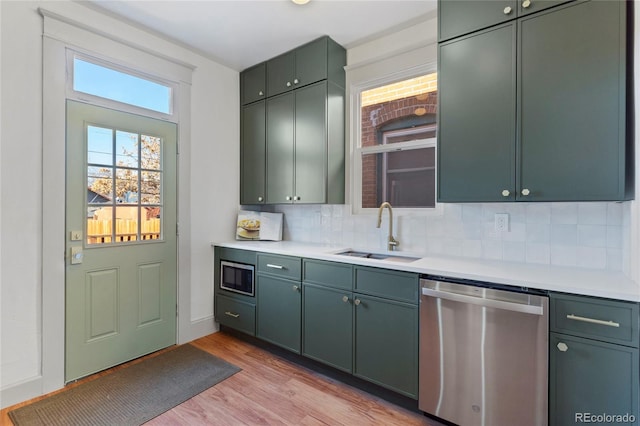 kitchen featuring appliances with stainless steel finishes, light hardwood / wood-style flooring, backsplash, and sink