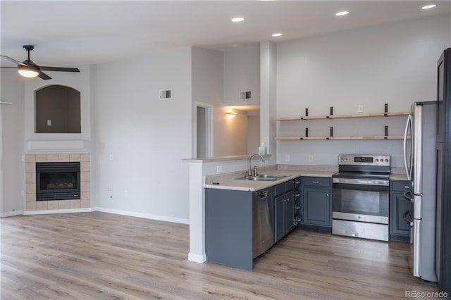 kitchen featuring a fireplace, open shelves, light countertops, appliances with stainless steel finishes, and a sink