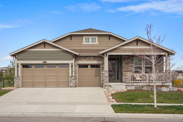craftsman house featuring stone siding, driveway, covered porch, and a garage