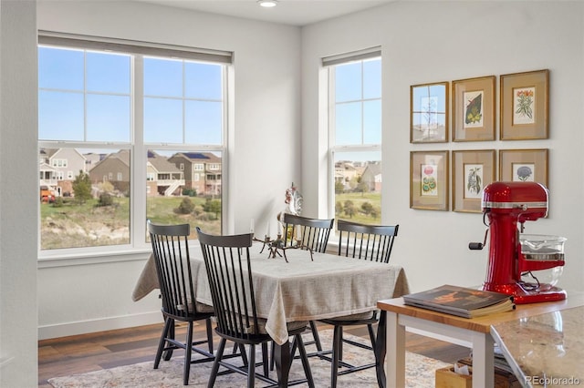 dining space with baseboards, wood finished floors, and recessed lighting