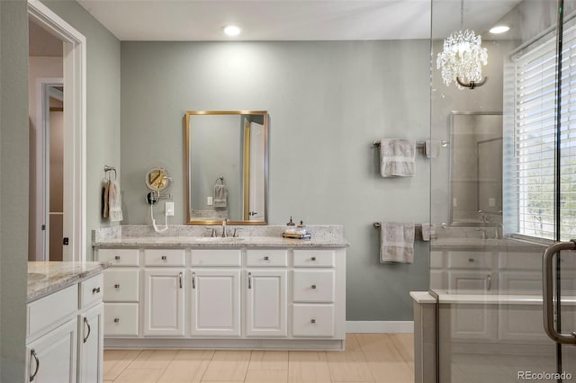 bathroom with a shower with shower door, vanity, and a notable chandelier