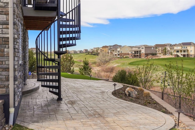 view of patio featuring stairway, fence, and a residential view