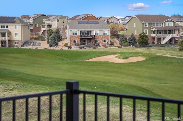 view of property's community with a yard, a residential view, golf course view, and fence
