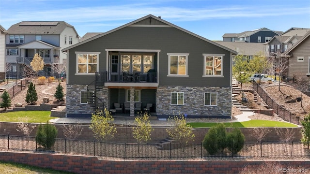 back of house with stairs, a patio area, stone siding, and a fenced backyard