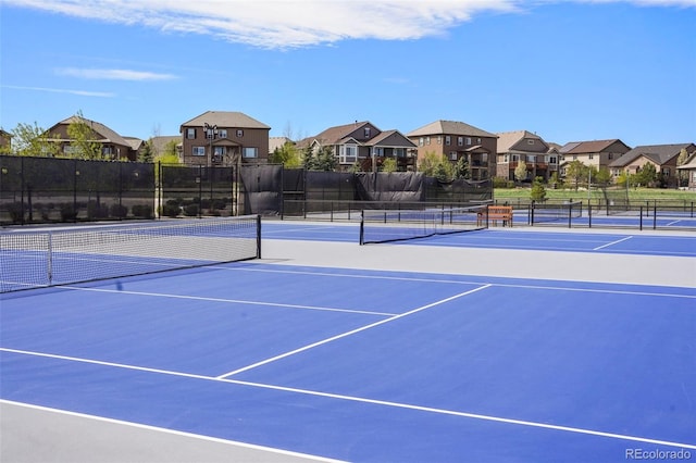 view of tennis court featuring a residential view and fence