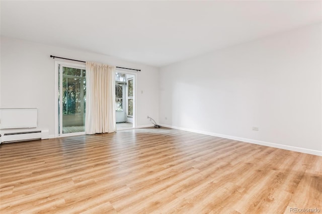 empty room featuring light hardwood / wood-style floors and a baseboard heating unit