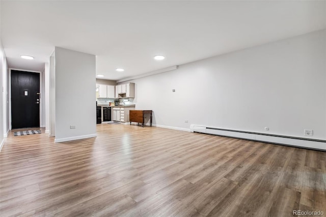 unfurnished living room featuring a baseboard radiator and light hardwood / wood-style flooring