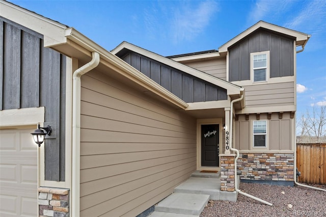 9840 Castor Dr, Colorado Springs, CO 80925 - view of exterior entry with fence, stone siding, board and batten siding, and a garage