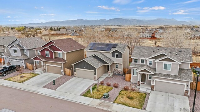9840 Castor Dr, Colorado Springs, CO 80925 - view of front of property featuring stone siding, a garage, a residential view, driveway, and a mountain view