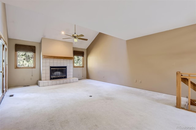 unfurnished living room featuring lofted ceiling, light colored carpet, ceiling fan, and a tile fireplace