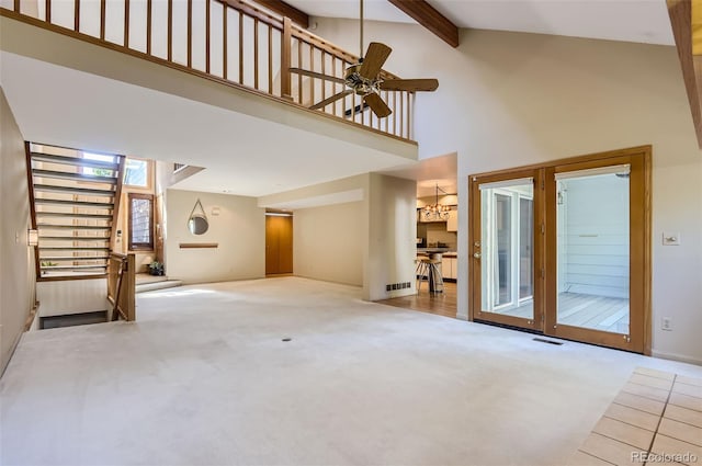 unfurnished living room with ceiling fan with notable chandelier, beamed ceiling, high vaulted ceiling, and carpet floors