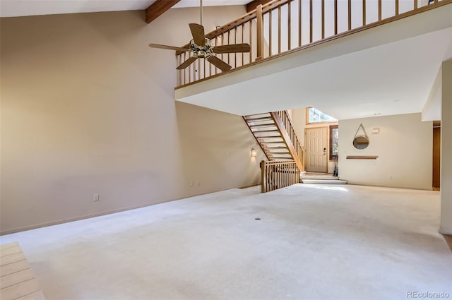 unfurnished living room featuring carpet flooring, high vaulted ceiling, beamed ceiling, and ceiling fan