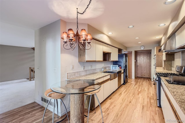 kitchen with hanging light fixtures, appliances with stainless steel finishes, an inviting chandelier, and light hardwood / wood-style floors