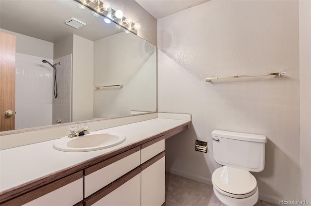 bathroom with vanity, toilet, a tile shower, and tile patterned flooring