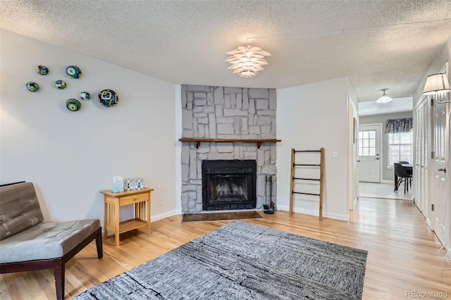 8136 Washington St Unit 141, Denver, CO 80229 - living area featuring a textured ceiling, wood finished floors, a fireplace, and baseboards