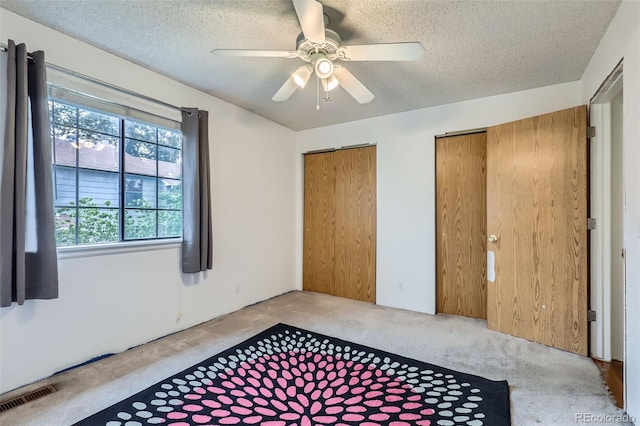 8136 Washington St Unit 141, Denver, CO 80229 - unfurnished bedroom featuring multiple closets, carpet flooring, a textured ceiling, and a ceiling fan