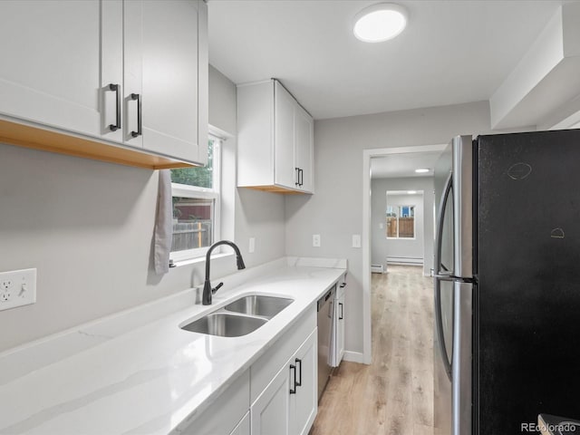 kitchen with light hardwood / wood-style flooring, white cabinetry, light stone countertops, sink, and stainless steel appliances