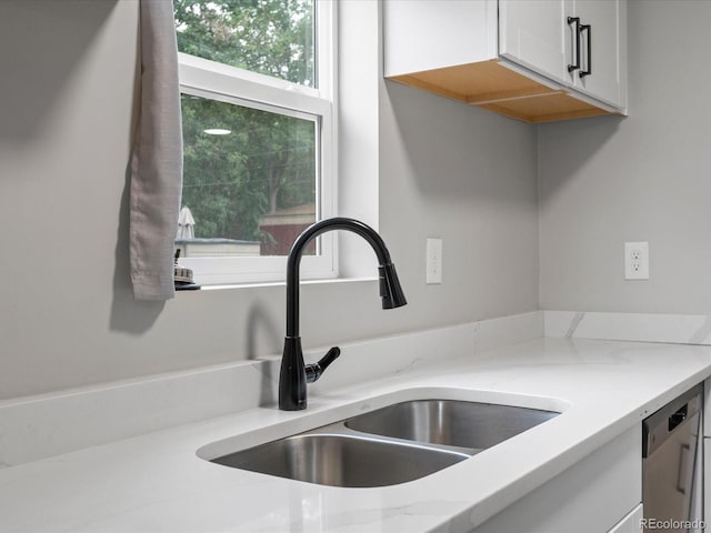 details featuring sink, white cabinetry, light stone countertops, and dishwasher