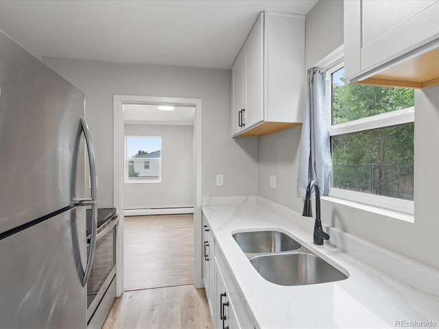 kitchen with a wealth of natural light, light hardwood / wood-style flooring, sink, and stainless steel refrigerator