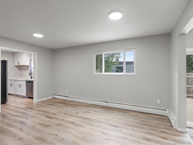 unfurnished living room featuring light hardwood / wood-style floors, a baseboard heating unit, and sink