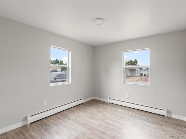 unfurnished room featuring a wealth of natural light, light hardwood / wood-style flooring, and a baseboard heating unit