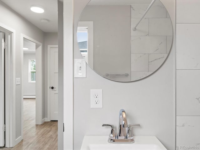 bathroom featuring sink, a baseboard heating unit, and hardwood / wood-style floors