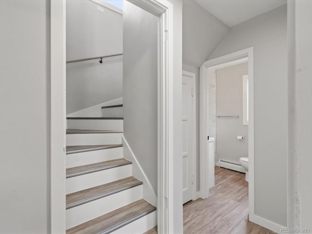 staircase with hardwood / wood-style flooring, lofted ceiling, and a baseboard radiator