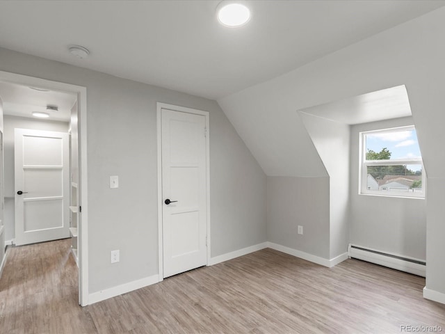 additional living space with light hardwood / wood-style flooring, a baseboard heating unit, and lofted ceiling