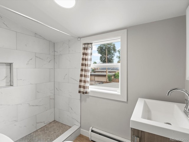 bathroom with tiled shower, sink, and baseboard heating