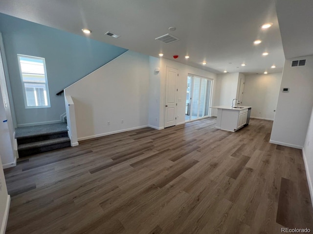 6638 N Nepal Ct, Aurora, CO 80019 - unfurnished living room with stairs, wood finished floors, baseboards, recessed lighting, and a sink