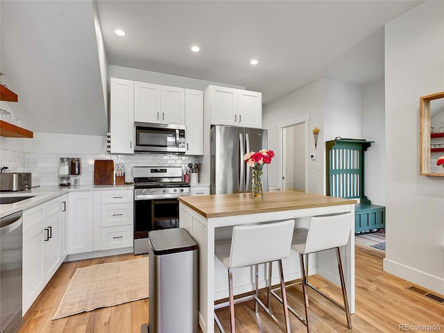 1303 Jersey St, Denver, CO 80220 - kitchen with appliances with stainless steel finishes, tasteful backsplash, a breakfast bar, white cabinets, and recessed lighting