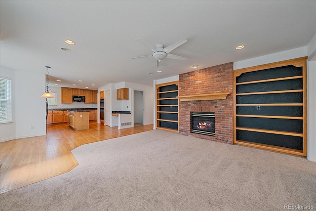 unfurnished living room with a ceiling fan, baseboards, recessed lighting, and a brick fireplace