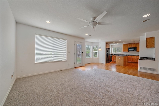 unfurnished living room with a ceiling fan, visible vents, baseboards, light carpet, and recessed lighting