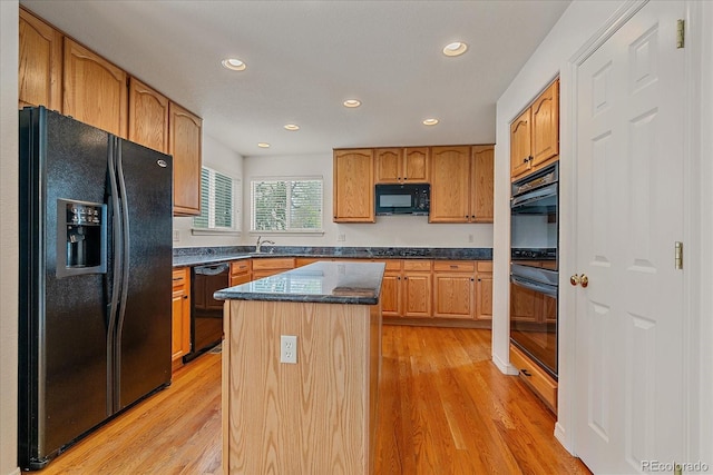 kitchen featuring light wood-type flooring, a kitchen island, black appliances, and recessed lighting