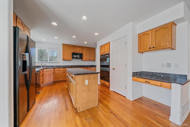 kitchen with a sink, light wood-type flooring, black appliances, recessed lighting, and a center island