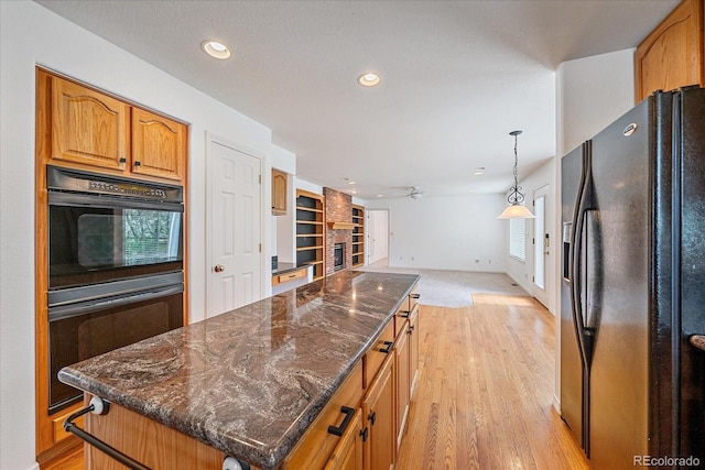 kitchen with dark stone countertops, black appliances, recessed lighting, open floor plan, and a kitchen island