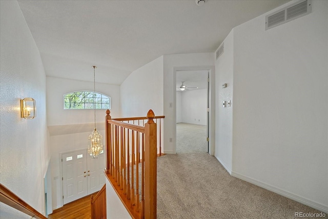 corridor with carpet, visible vents, an upstairs landing, and baseboards
