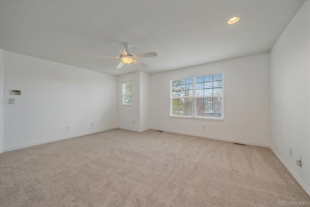 empty room featuring visible vents, recessed lighting, light carpet, a ceiling fan, and baseboards
