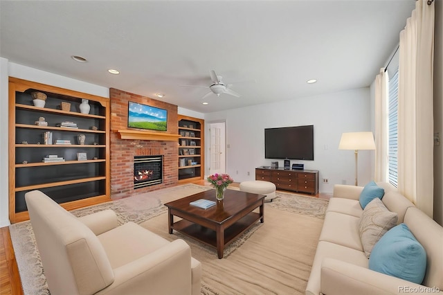 living room with wood finished floors, built in shelves, a fireplace, ceiling fan, and recessed lighting