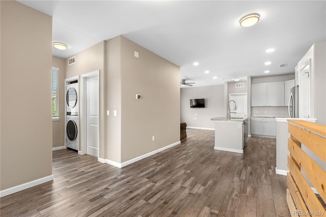 847 E 98th Ave Unit 1806, Thornton, CO 80229 - kitchen featuring open floor plan, stacked washing machine and dryer, dark wood-style floors, light countertops, and a kitchen island with sink