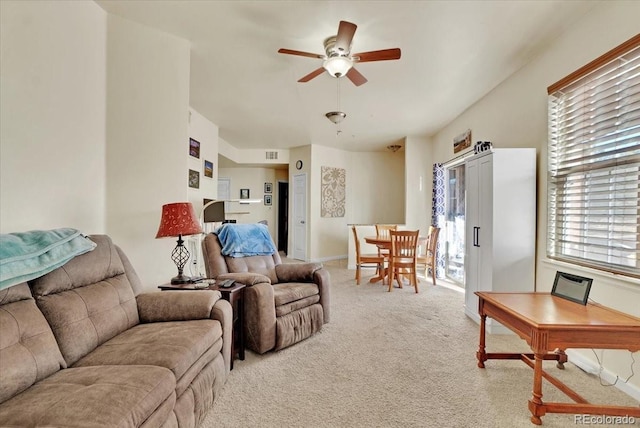 living area with light carpet, visible vents, and a ceiling fan