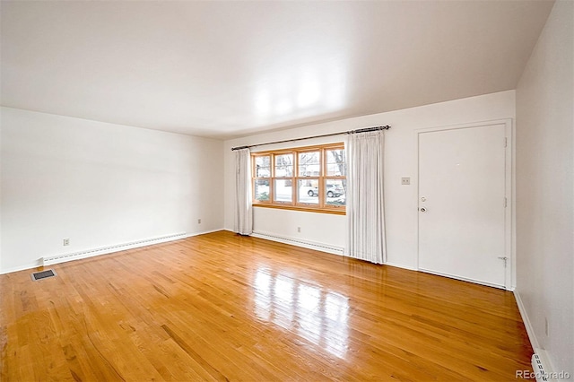 spare room featuring hardwood / wood-style flooring and a baseboard heating unit