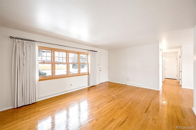 spare room with a baseboard radiator and light wood-type flooring