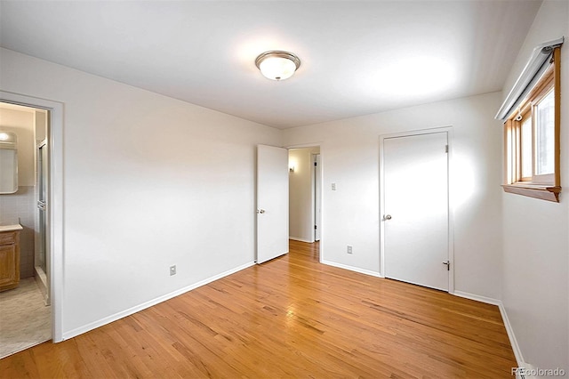 unfurnished bedroom with ensuite bath and light wood-type flooring