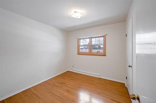 unfurnished room with a baseboard heating unit and light hardwood / wood-style floors