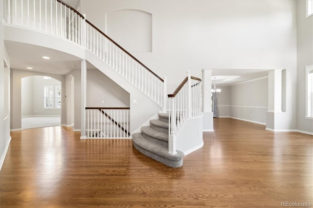 3901 Stonegrass Pt, Broomfield, CO 80023 - stairway featuring a towering ceiling, arched walkways, a chandelier, and wood finished floors