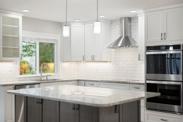 3901 Stonegrass Pt, Broomfield, CO 80023 - kitchen featuring stainless steel appliances, wall chimney range hood, decorative backsplash, white cabinetry, and recessed lighting