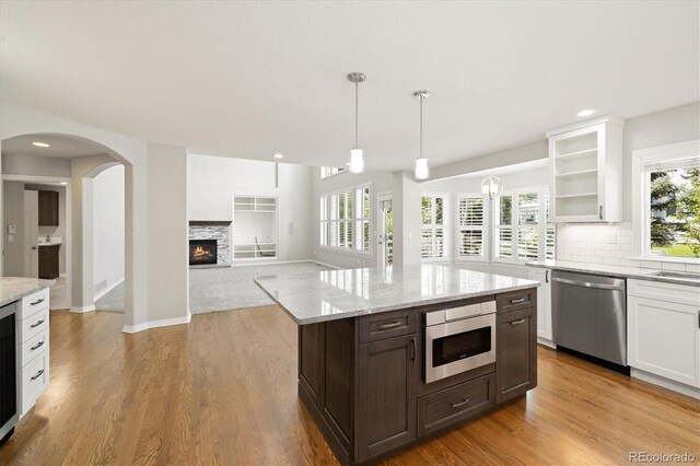 3901 Stonegrass Pt, Broomfield, CO 80023 - kitchen featuring stainless steel dishwasher, white cabinets, a fireplace, wood finished floors, and recessed lighting