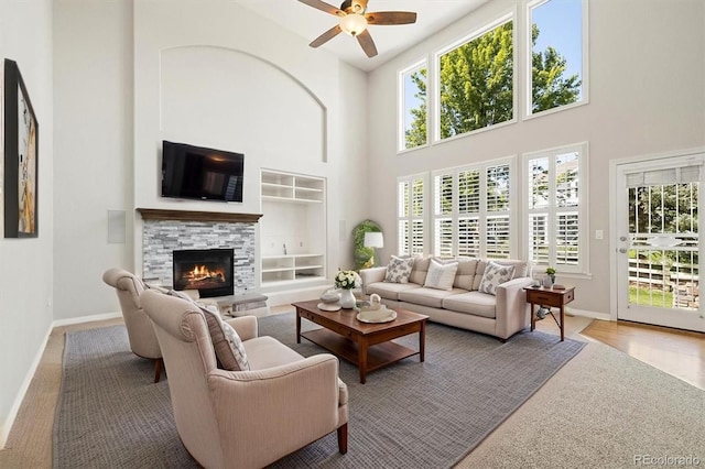 3901 Stonegrass Pt, Broomfield, CO 80023 - living area featuring ceiling fan, a high ceiling, a warm lit fireplace, healthy amount of natural light, and carpet flooring