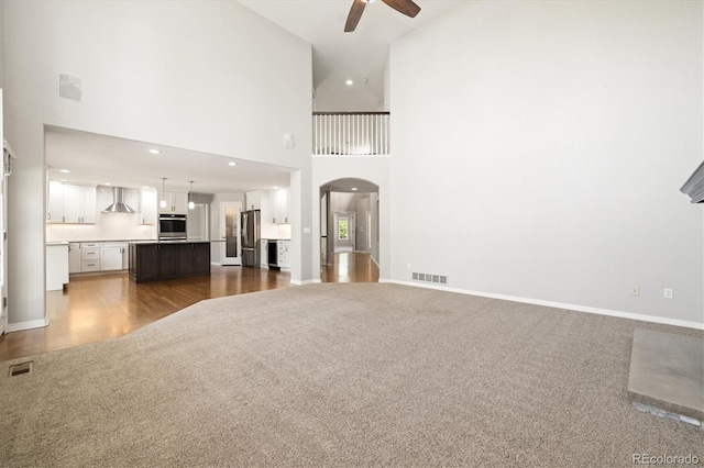 3901 Stonegrass Pt, Broomfield, CO 80023 - unfurnished living room featuring a ceiling fan, dark colored carpet, arched walkways, a towering ceiling, and recessed lighting